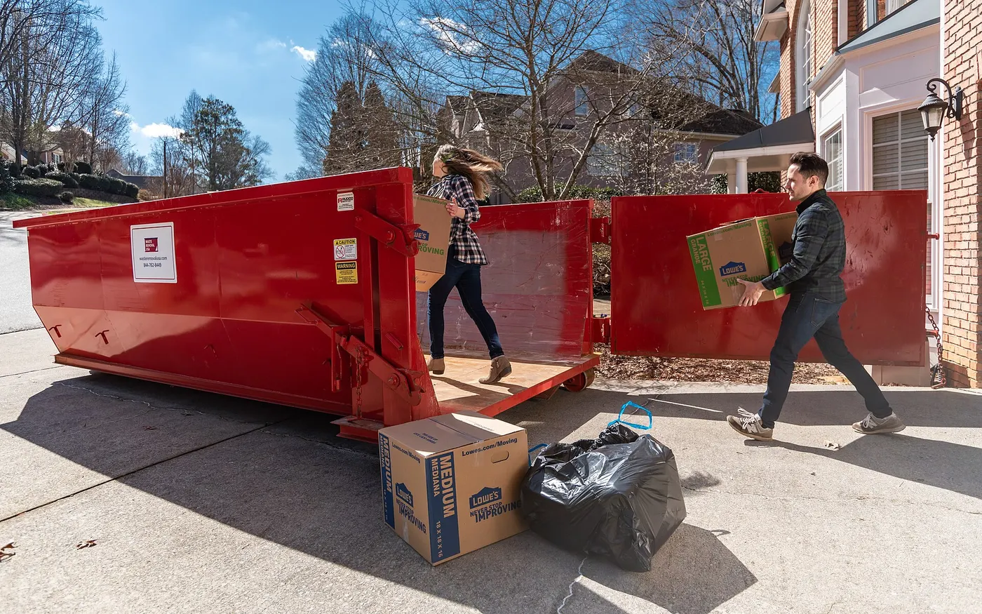 Roll-off dumpster in a driveway being loaded during a home cleanout